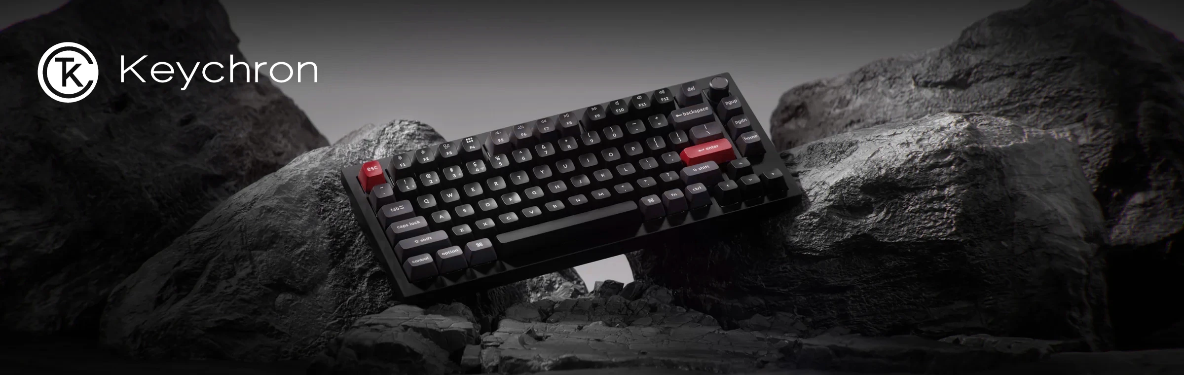 Keychron mechanisch toetsenbord met zwarte toetsen en rode esc- en enter-toets op rotsen onder het Keychron logo