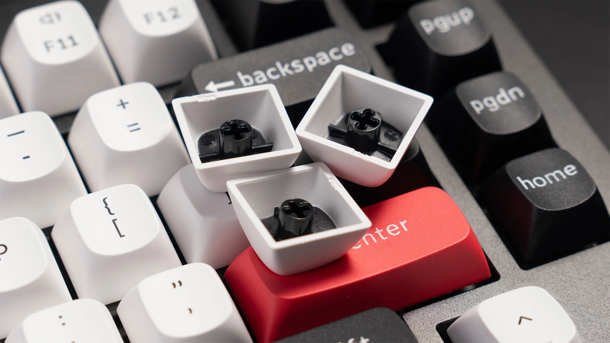 Close-up van Keychron toetsenbord met verwijderde witte toetsenkappen die de hot-swap sockets en rode entertoets tonen