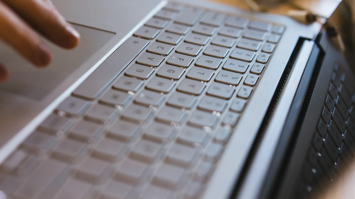 Close-up van een laptoptoetsenbord met een hand die naar de toetsen reikt