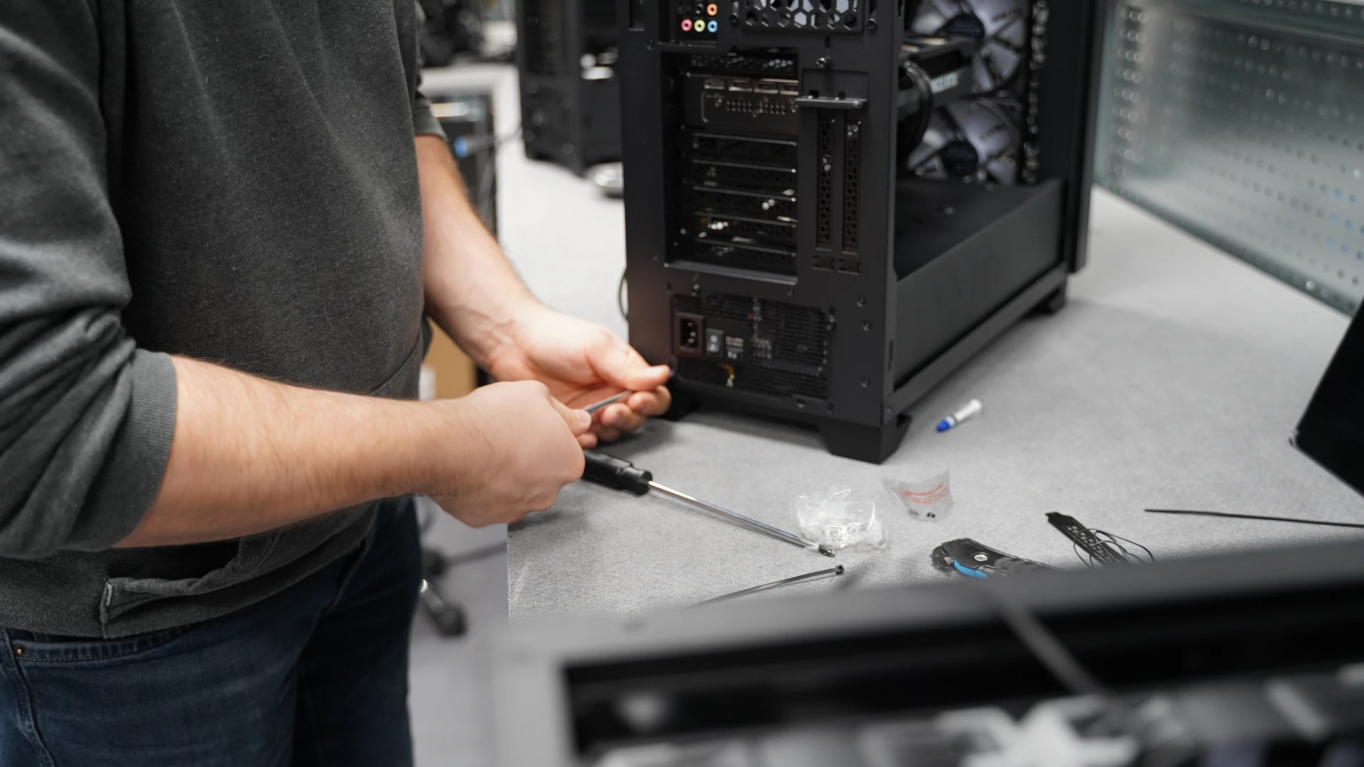 Compacte zwarte pc met houten frontpaneel naast gaming monitor